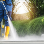 Homeowner pressure washing a concrete paver patio with a fan-tip nozzle