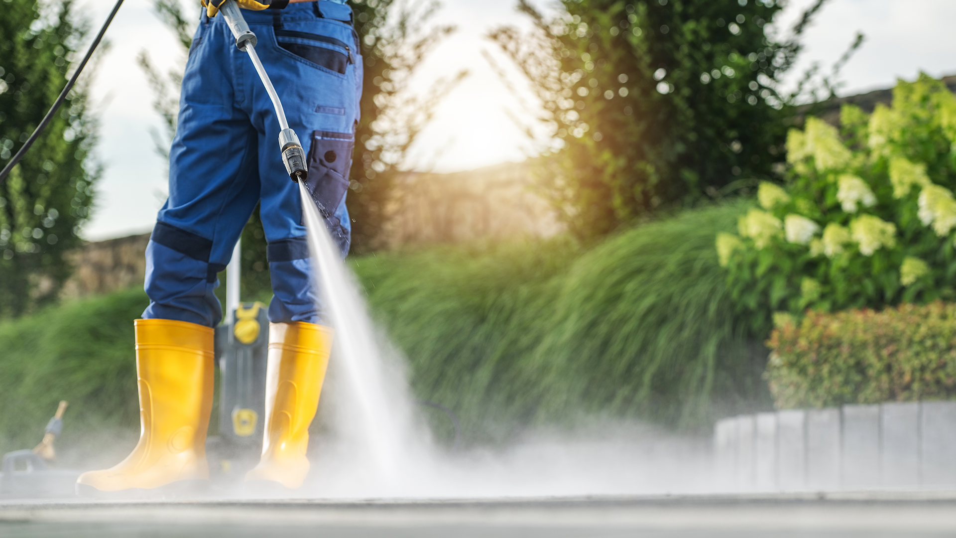 Homeowner pressure washing a concrete paver patio with a fan-tip nozzle